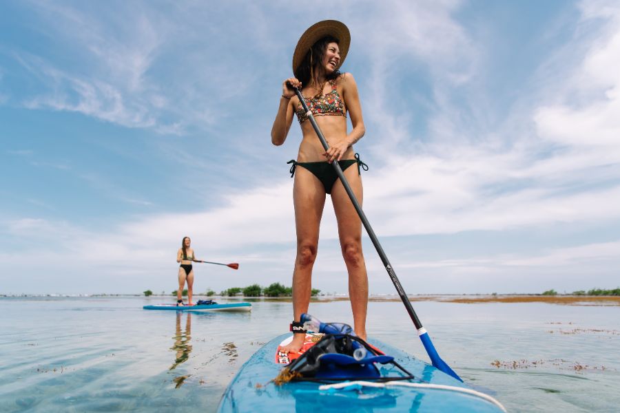 Female couple paddle boarding in belize