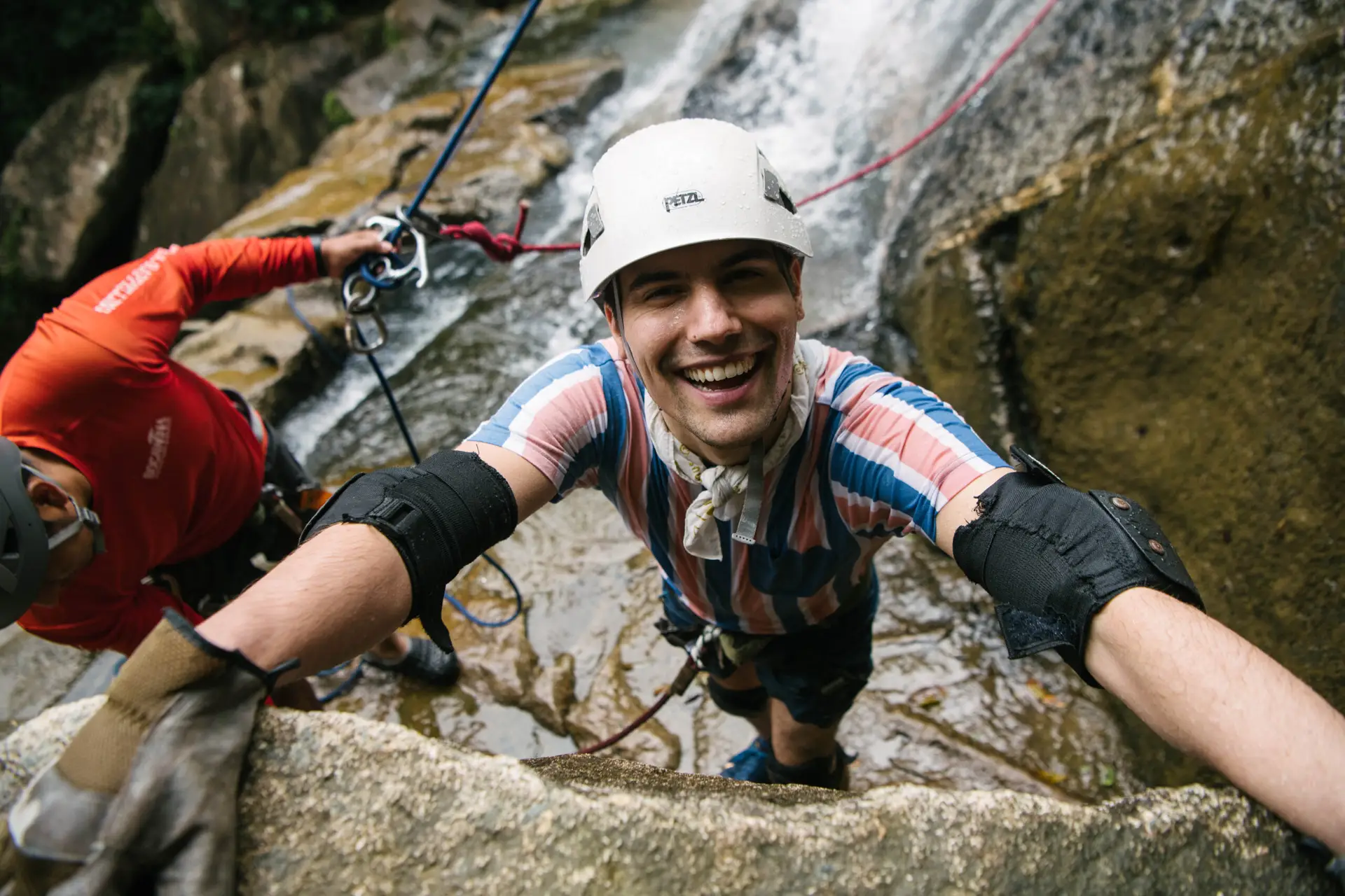 Person smiling at bottom of waterfall rappel in Belize