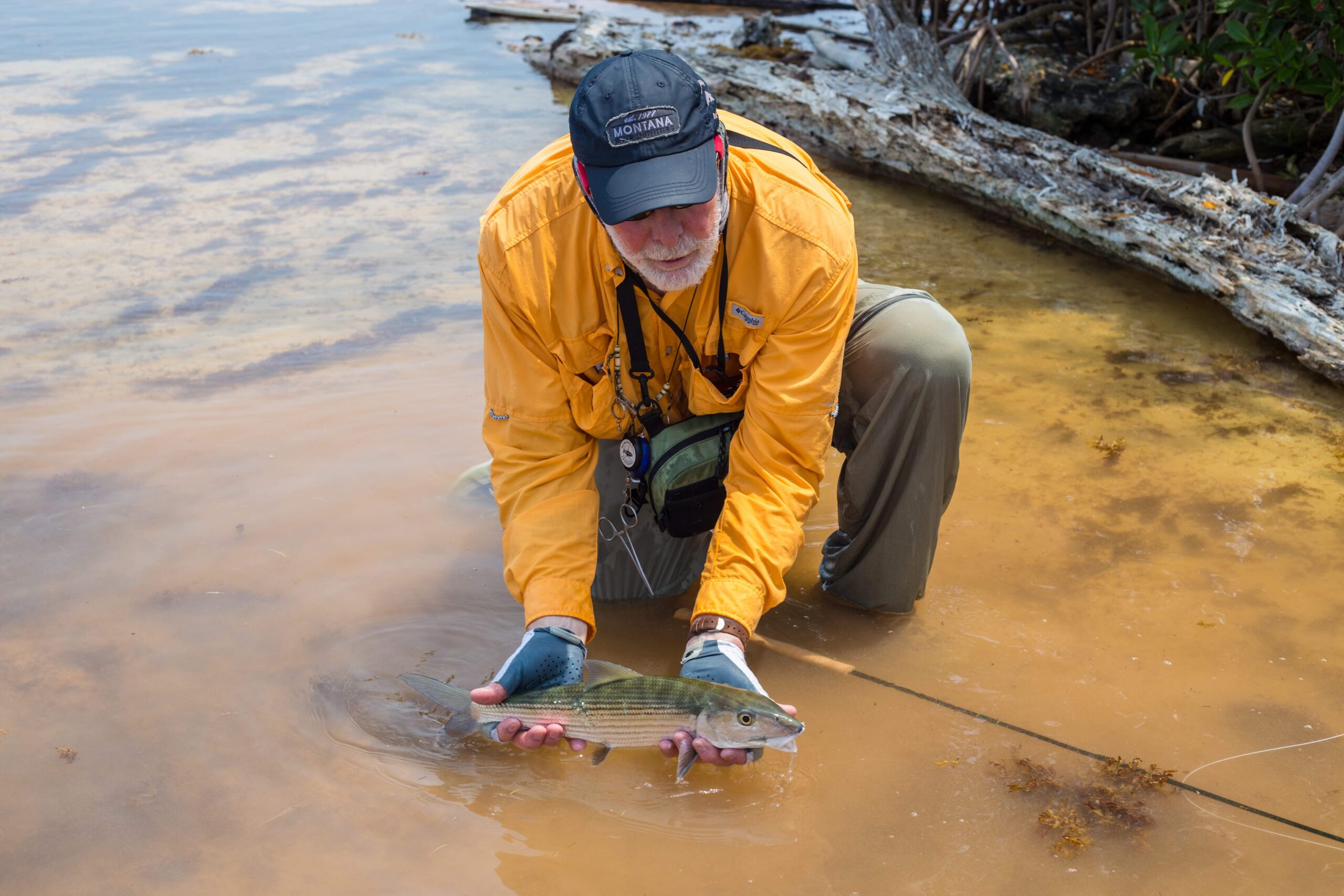 angler posing with a Bonefish that he caught while fly-fishing in Belize