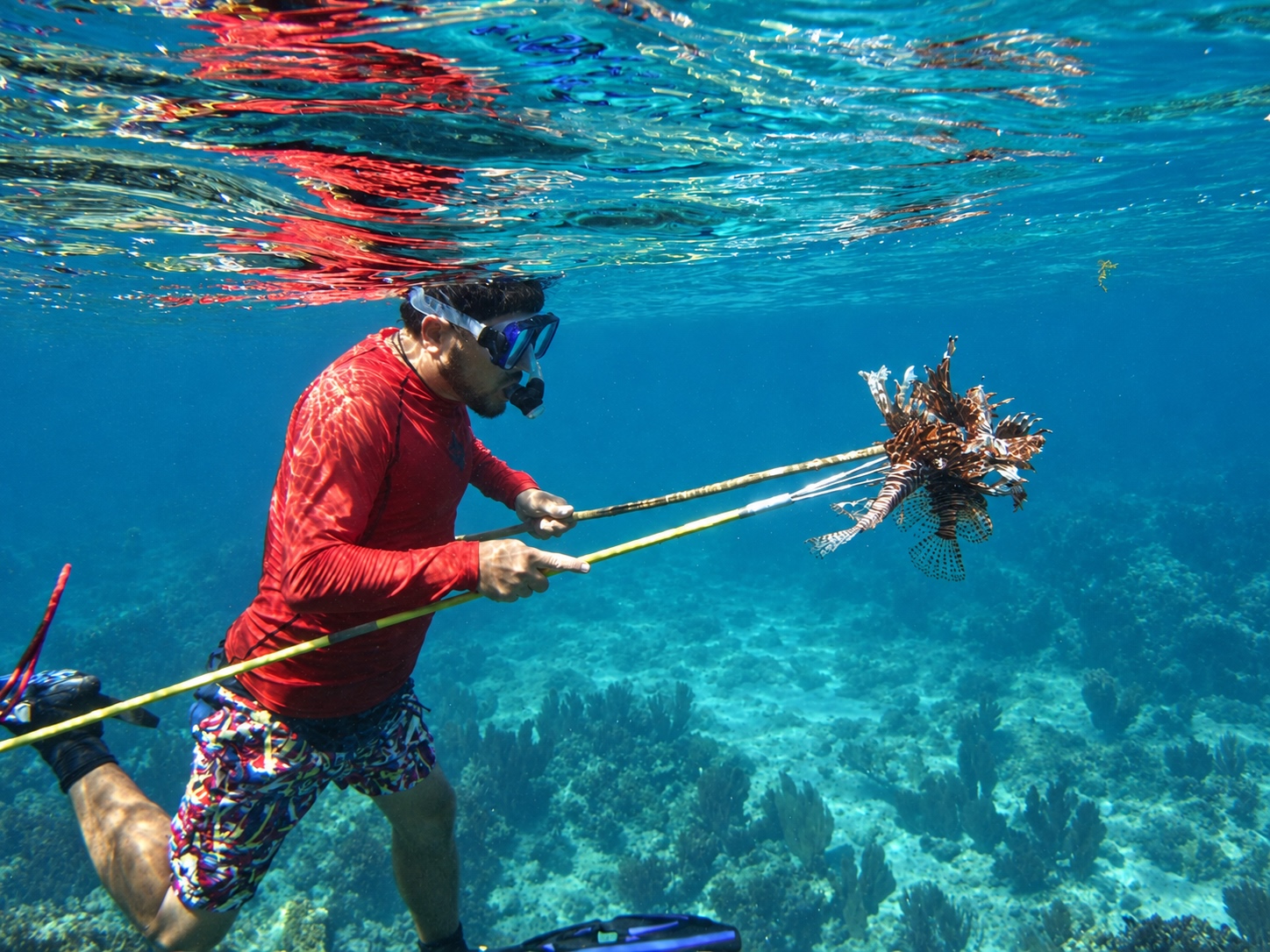 guide in Belize with two Lionfish on a spear