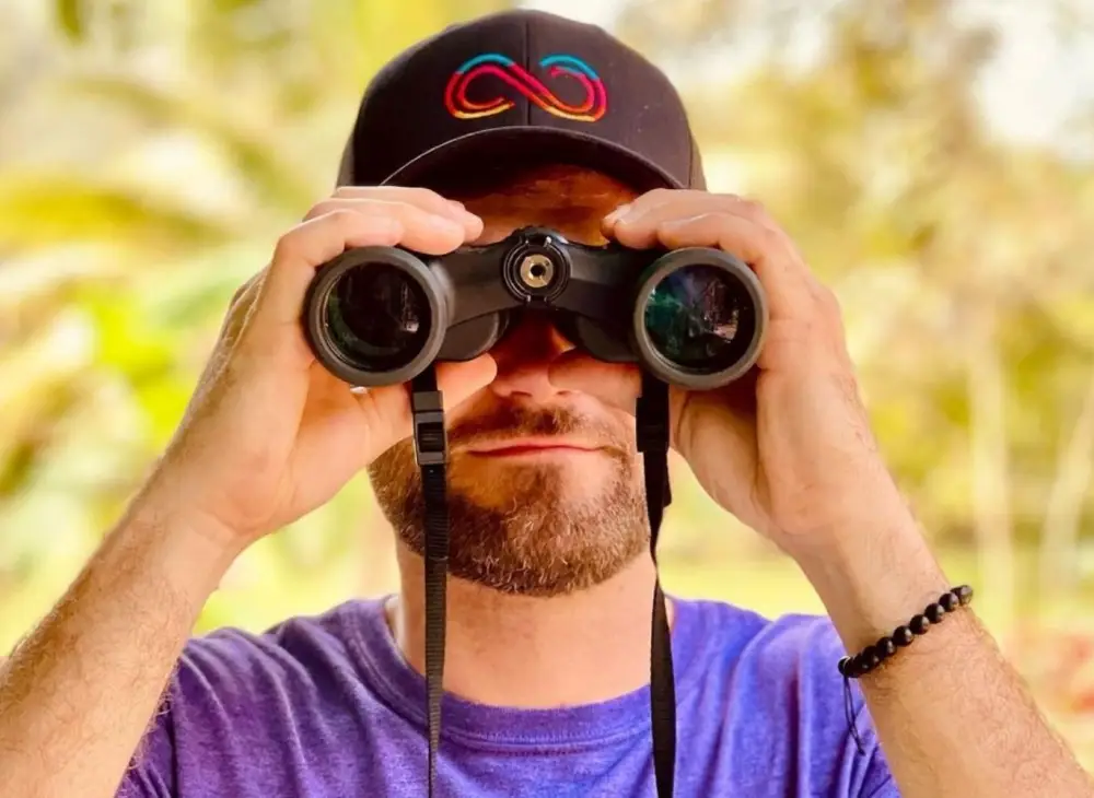 person looks through binoculars during a birding tour at Bocawina in Belize