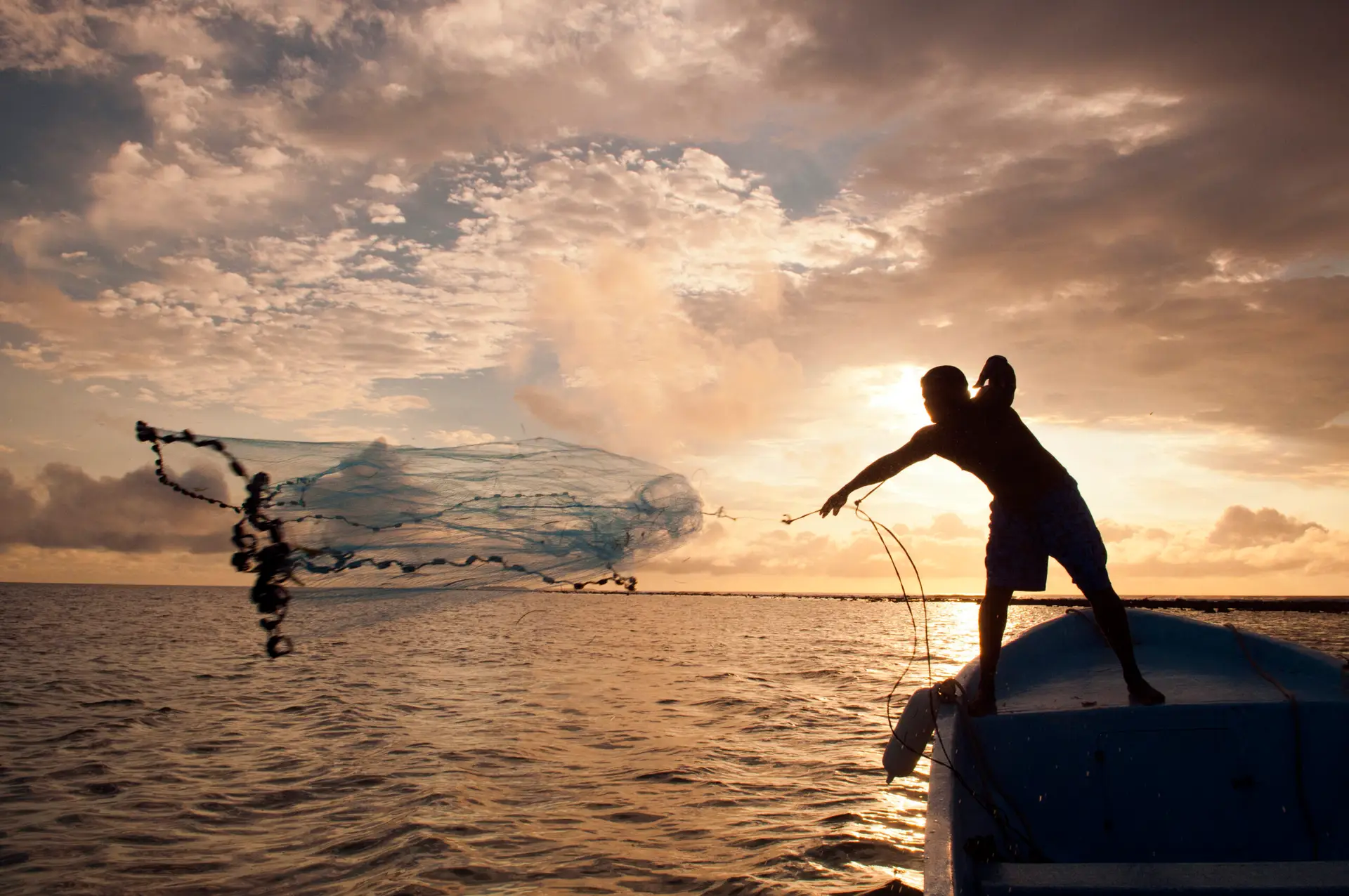 Fisherman in Belize casting a throw-net at sunset in Belize